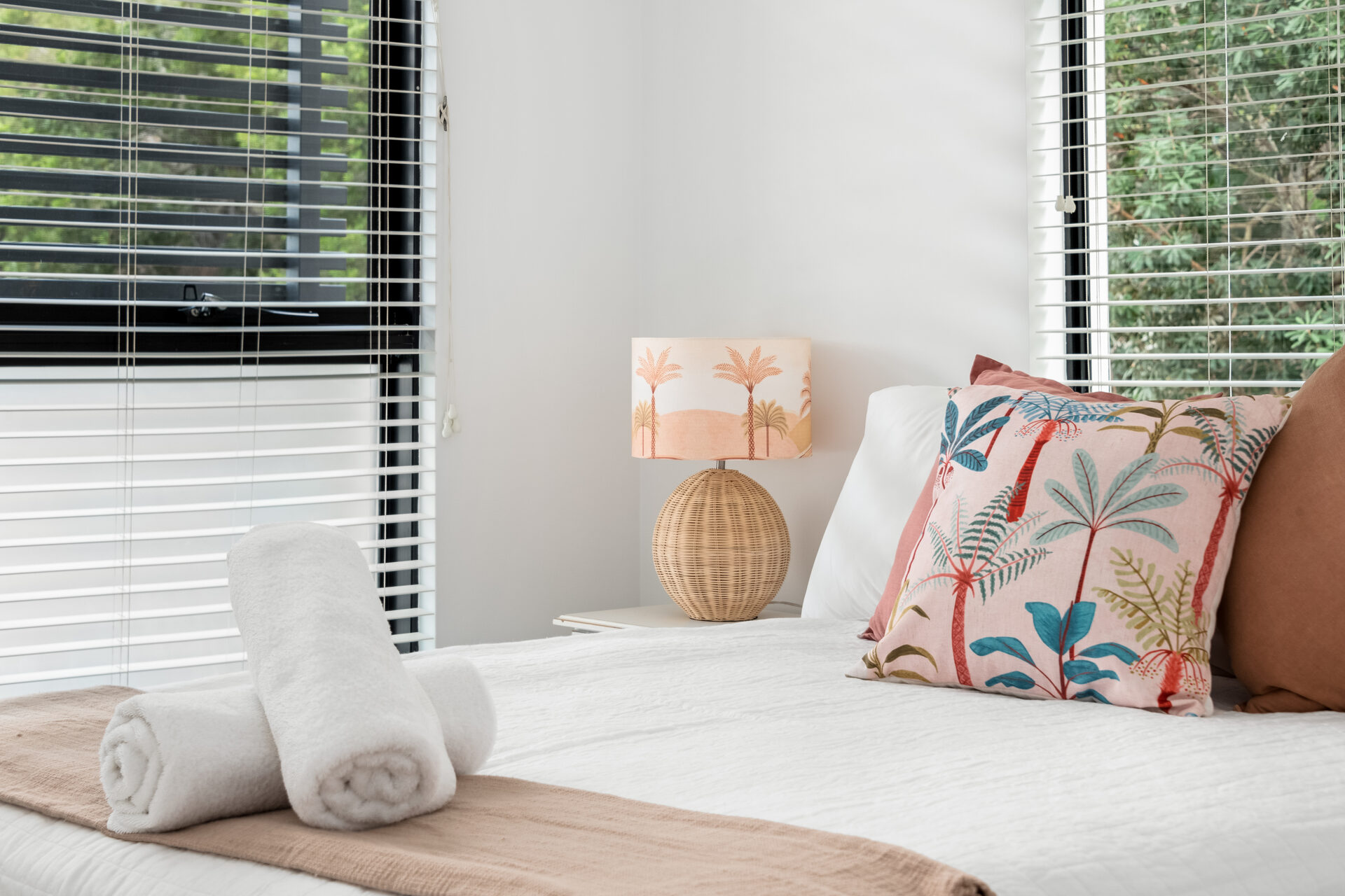 Bed detail with rolled towels and tropical lamp