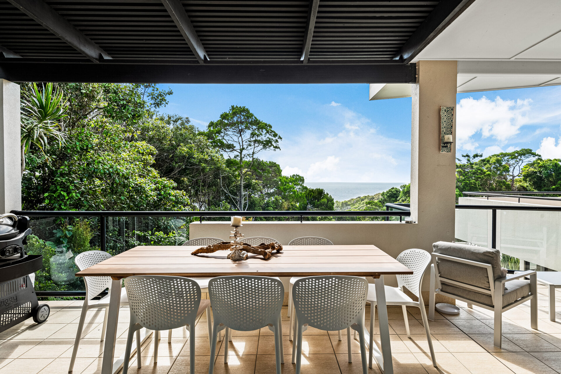 Outdoor dining table with BBQ and ocean backdrop