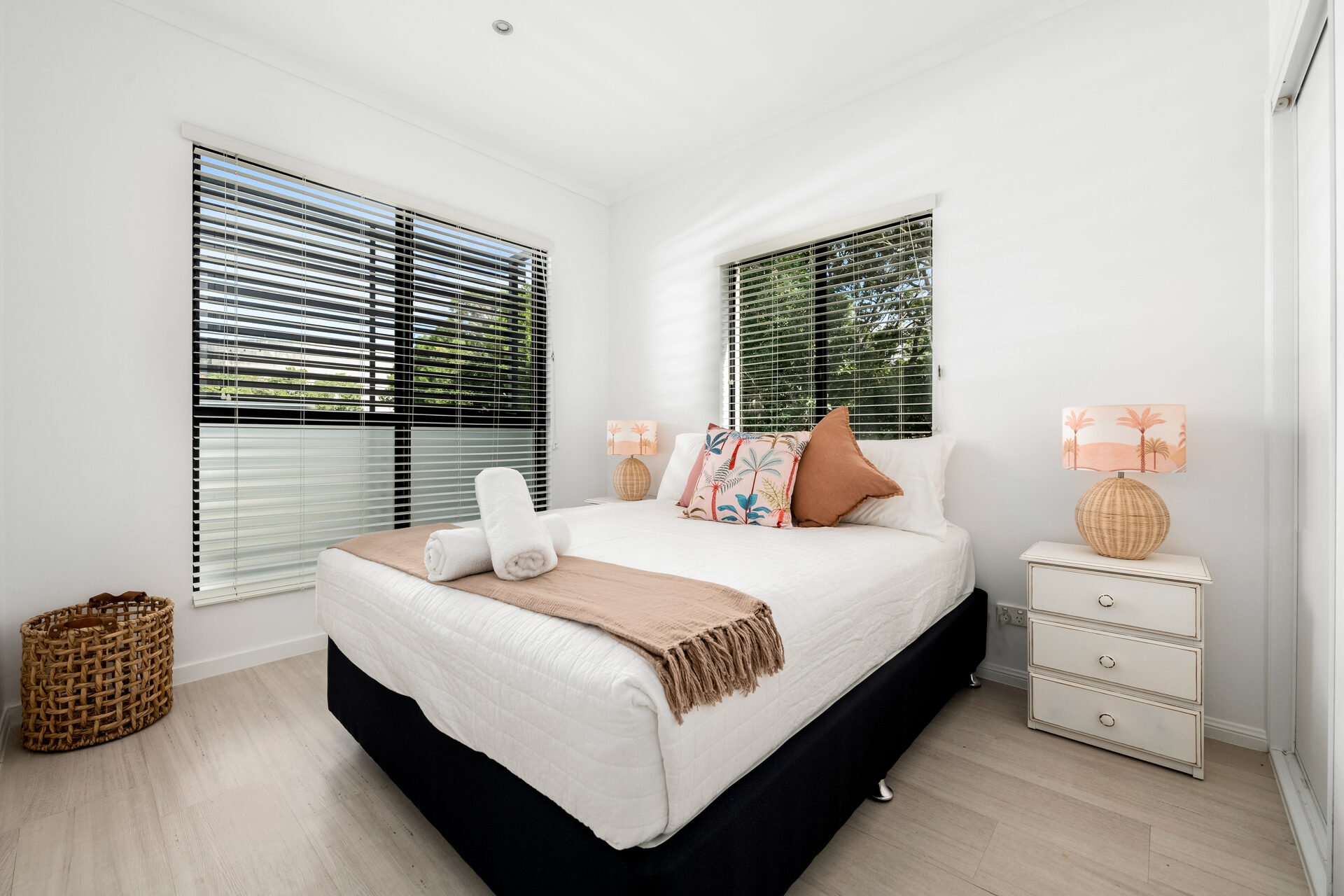 Queen bedroom with tropical styling and rattan lamps