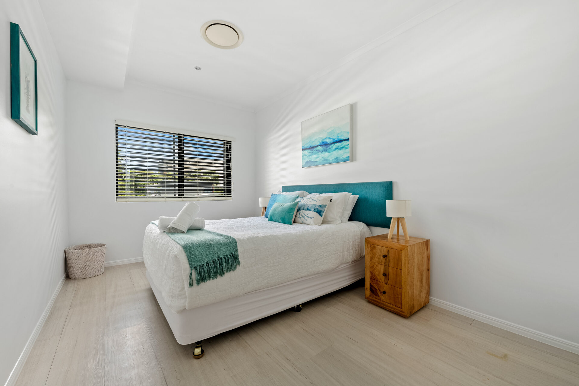 Queen bedroom with teal headboard and coastal art